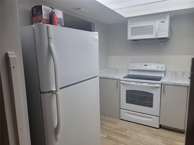 kitchen with white appliances and light hardwood / wood-style flooring