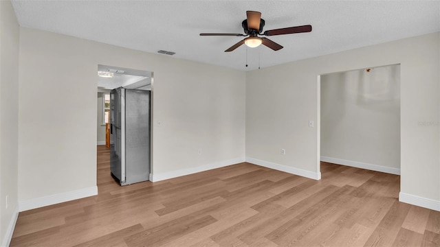 unfurnished room featuring a textured ceiling, light wood-type flooring, and ceiling fan