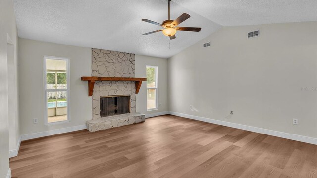 unfurnished living room with ceiling fan, light wood-type flooring, vaulted ceiling, and a fireplace