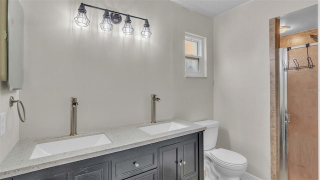 bathroom with a shower with shower door, double vanity, and toilet