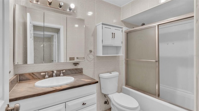 full bathroom featuring decorative backsplash, toilet, tile walls, enclosed tub / shower combo, and vanity