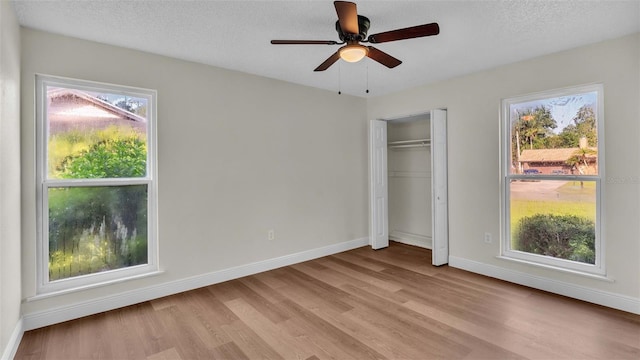 unfurnished bedroom featuring ceiling fan, a textured ceiling, light hardwood / wood-style floors, and a closet