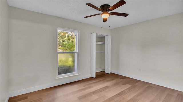 unfurnished bedroom with a textured ceiling, a closet, ceiling fan, and light hardwood / wood-style floors