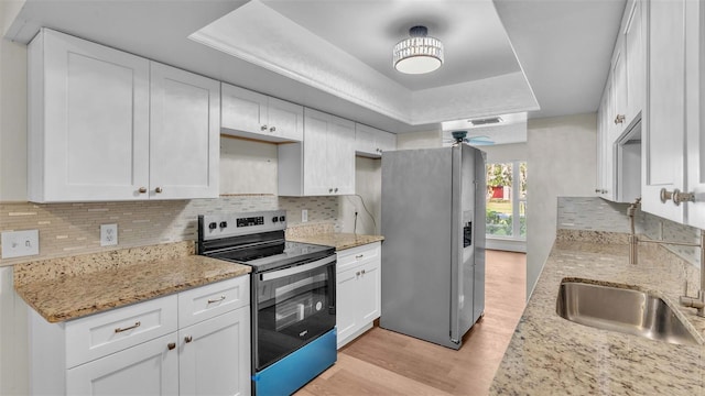 kitchen featuring stainless steel appliances, light hardwood / wood-style floors, white cabinetry, ceiling fan, and decorative backsplash