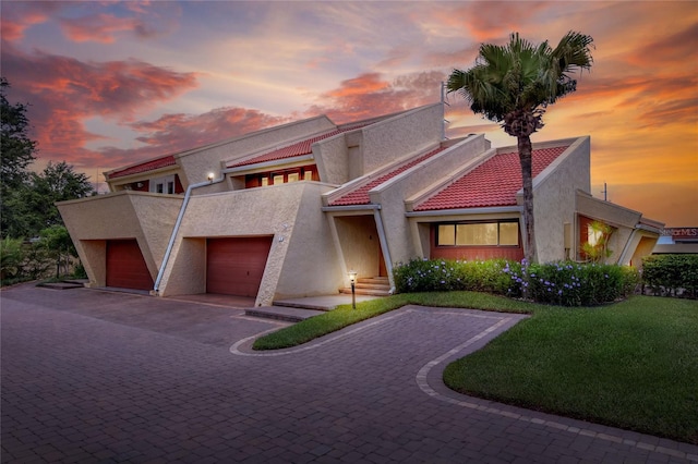 view of front of home featuring a garage, decorative driveway, a tile roof, and stucco siding