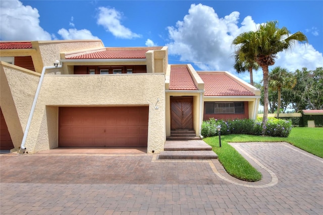 view of front of house featuring a garage, a tiled roof, decorative driveway, and stucco siding