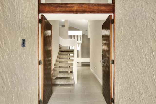 stairs with a textured wall, baseboards, and tile patterned floors