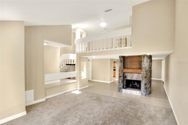 unfurnished living room with high vaulted ceiling, light colored carpet, and a stone fireplace