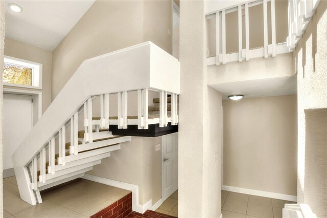 stairs with tile patterned floors and high vaulted ceiling