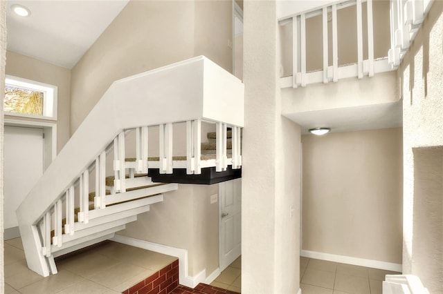 stairs with a high ceiling, baseboards, and tile patterned floors