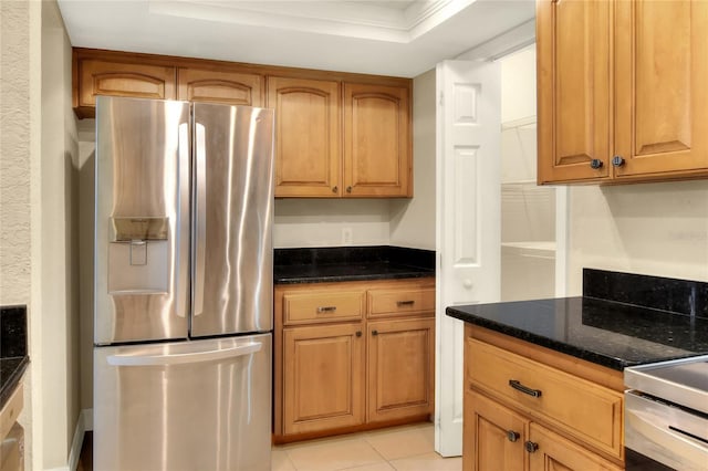 kitchen with a raised ceiling, stainless steel refrigerator with ice dispenser, light tile patterned flooring, and dark stone counters