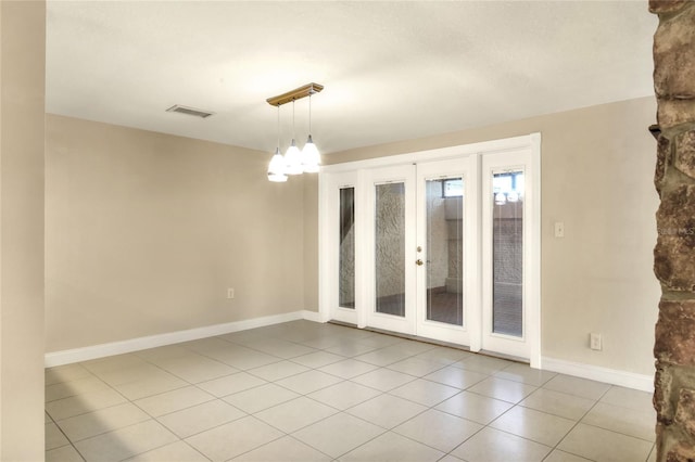 unfurnished room featuring a chandelier, light tile patterned flooring, visible vents, and baseboards