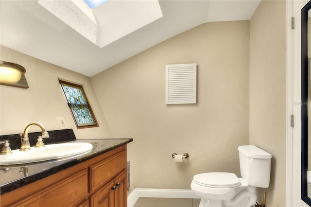 bathroom featuring tile patterned flooring, toilet, vanity, baseboards, and lofted ceiling with skylight