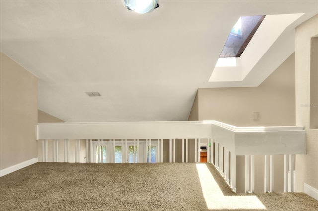 hall featuring vaulted ceiling with skylight, carpet floors, and baseboards