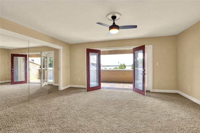 carpeted empty room featuring ceiling fan, french doors, and baseboards