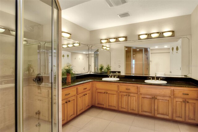 bathroom featuring double sink vanity, a shower with door, and tile patterned flooring