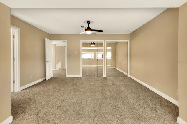 unfurnished bedroom featuring carpet floors, baseboards, ceiling fan, and multiple closets