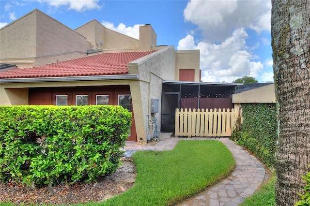 view of front of home with a chimney, fence, a front lawn, and stucco siding