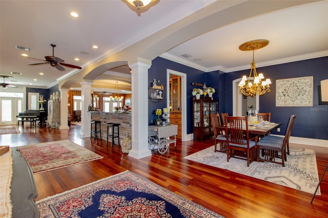 dining room featuring dark hardwood / wood-style floors, crown molding, ceiling fan with notable chandelier, and decorative columns