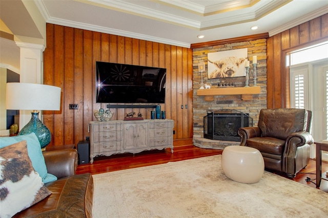 living room featuring dark hardwood / wood-style flooring, wooden walls, crown molding, and a fireplace