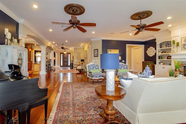 living room featuring hardwood / wood-style flooring, ornate columns, ceiling fan, and crown molding