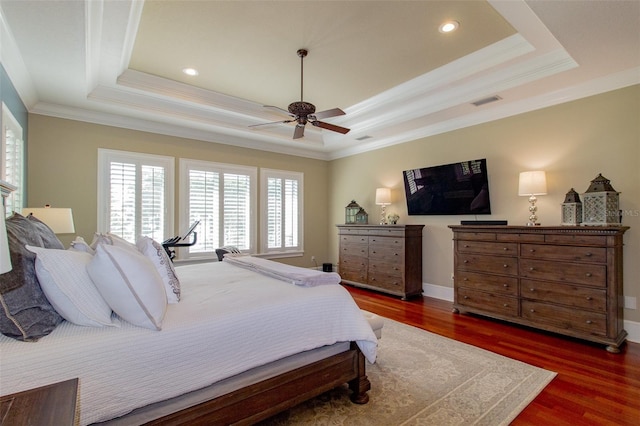 bedroom featuring dark hardwood / wood-style floors, ceiling fan, crown molding, and a tray ceiling