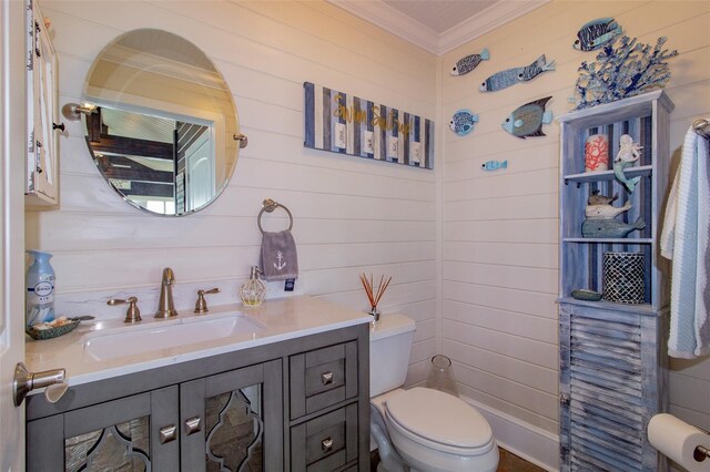 bathroom featuring vanity, wooden walls, toilet, and ornamental molding