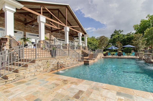 view of swimming pool featuring pool water feature, ceiling fan, and a patio