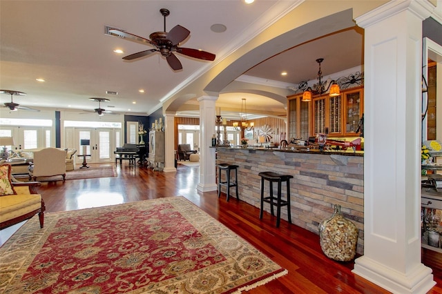 living room with french doors, ceiling fan with notable chandelier, crown molding, ornate columns, and dark hardwood / wood-style flooring