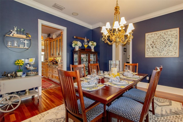 dining room with crown molding, hardwood / wood-style floors, and a chandelier