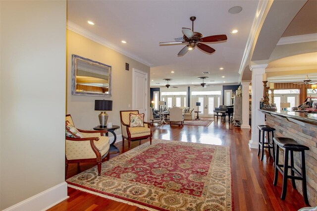 living room featuring dark hardwood / wood-style flooring, decorative columns, plenty of natural light, and crown molding