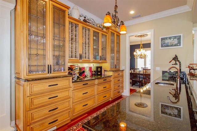 kitchen featuring dark stone counters, ornamental molding, sink, an inviting chandelier, and hanging light fixtures