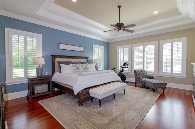 bedroom with dark hardwood / wood-style floors, multiple windows, a tray ceiling, and ceiling fan