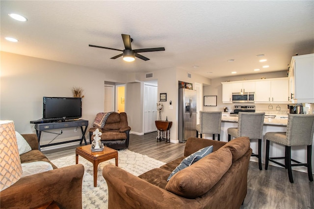 living room with a textured ceiling, dark hardwood / wood-style floors, and ceiling fan