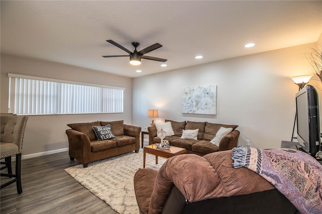 living room featuring dark wood-type flooring and ceiling fan