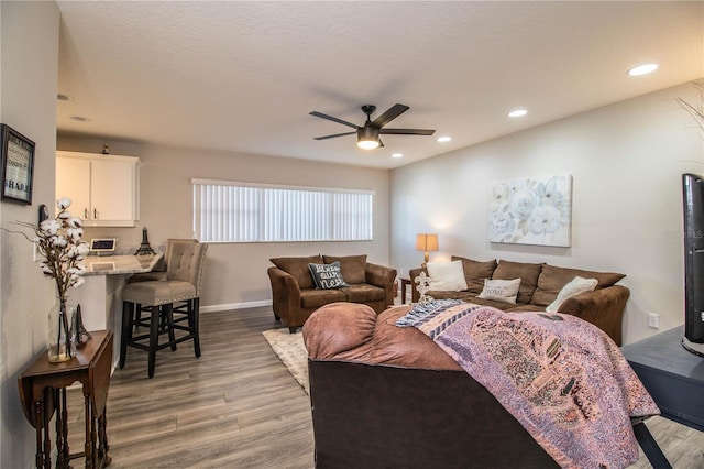 living room with ceiling fan, light hardwood / wood-style flooring, and a textured ceiling