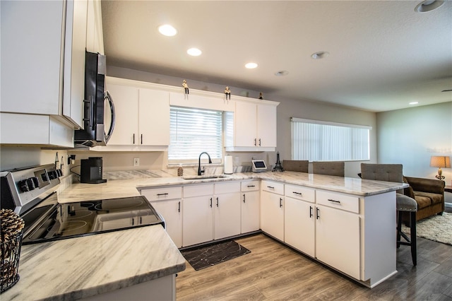 kitchen with appliances with stainless steel finishes, kitchen peninsula, sink, and white cabinets