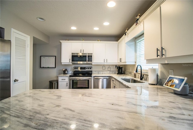 kitchen featuring white cabinetry, sink, stainless steel appliances, and light stone countertops