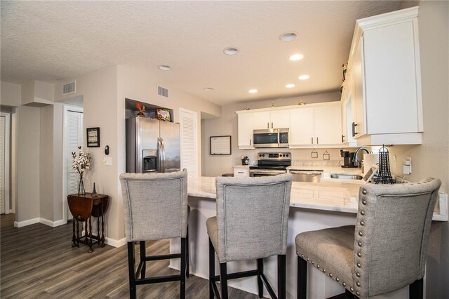 kitchen featuring sink, dark wood-type flooring, a breakfast bar area, white cabinetry, and stainless steel appliances