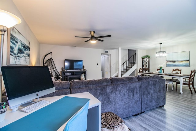 living room featuring wood-type flooring and ceiling fan with notable chandelier