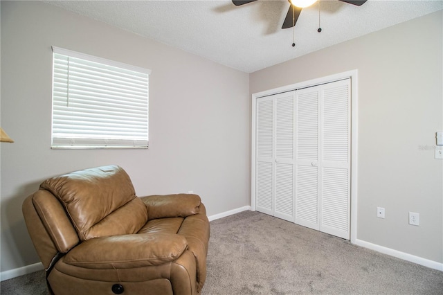 sitting room with ceiling fan, light colored carpet, and a textured ceiling