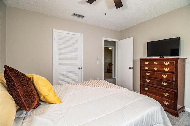 bedroom featuring ceiling fan, a closet, a textured ceiling, and carpet