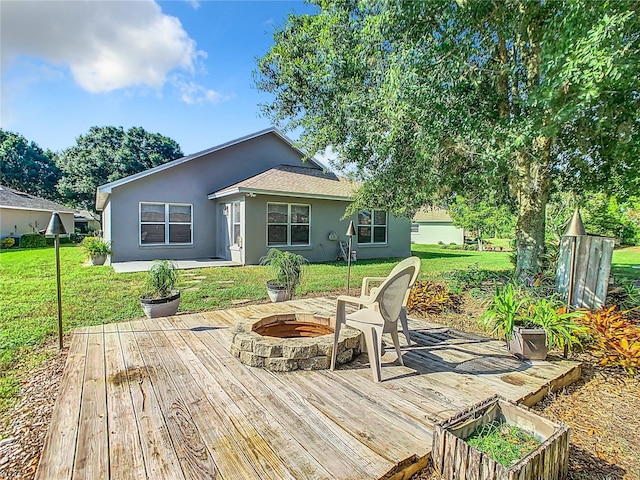 wooden deck with a fire pit and a lawn