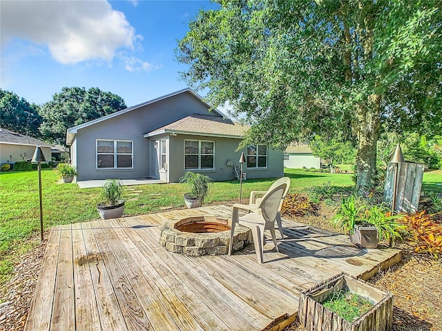 wooden terrace featuring a fire pit and a lawn