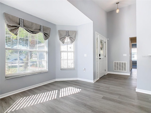 entrance foyer with visible vents, a towering ceiling, baseboards, and wood finished floors