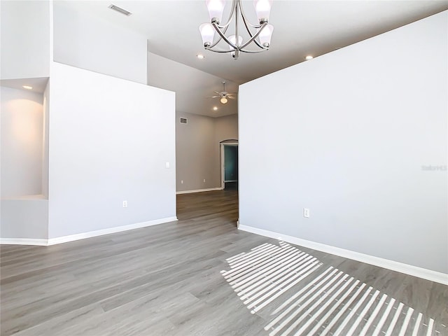 spare room featuring ceiling fan with notable chandelier, arched walkways, visible vents, and wood finished floors