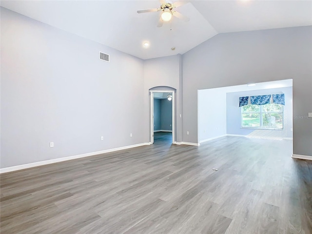 unfurnished living room with baseboards, visible vents, arched walkways, a ceiling fan, and wood finished floors