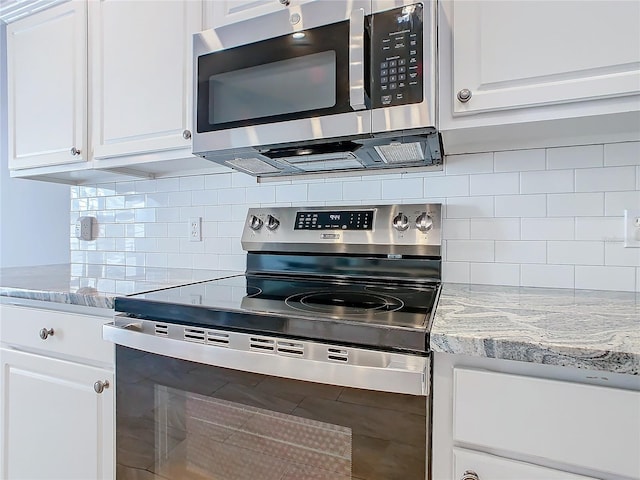 kitchen with white cabinets, tasteful backsplash, light stone counters, and stainless steel appliances