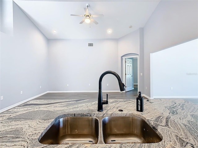 interior details with baseboards, visible vents, a ceiling fan, arched walkways, and a sink