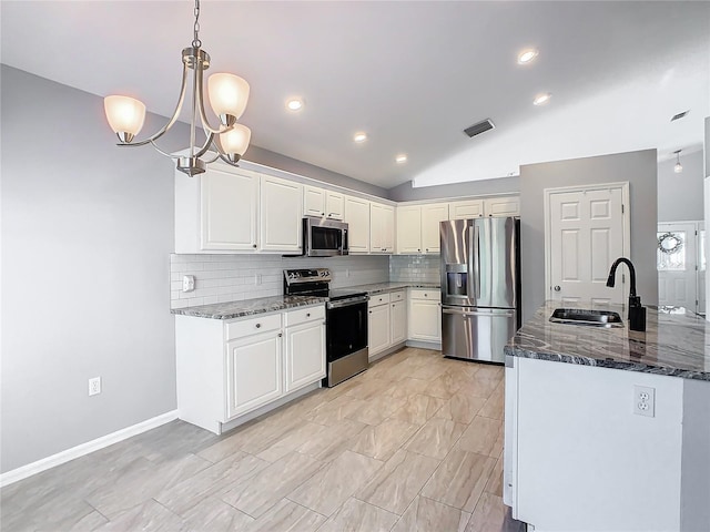 kitchen with stainless steel appliances, a sink, white cabinetry, hanging light fixtures, and dark stone counters